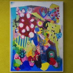 May include: Abstract painting with a colourful, layered design. The painting features a variety of shapes, colours, and textures, including red, blue, green, yellow, and white. The painting is framed and ready to hang.