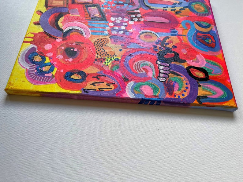 Puede incluir: Pintura abstracta sobre lienzo con fondo amarillo y remolinos, c&iacute;rculos y l&iacute;neas de colores en rosa, rojo, morado, azul y verde.