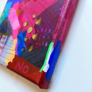 Puede incluir: Pintura abstracta sobre lienzo con un esquema de color rojo, rosa, morado, azul, negro, blanco y dorado. La pintura tiene una superficie texturizada y la palabra "NO" est&aacute; escrita en pintura roja en la esquina inferior derecha.