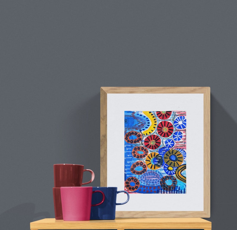 Pu&ograve; includere: Una stampa incorniciata di un dipinto astratto con cerchi e linee colorati su uno sfondo blu. Il dipinto &egrave; in una cornice di legno ed &egrave; appeso a un muro grigio.