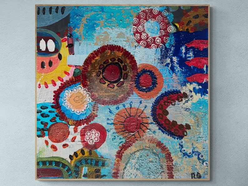 May include: Abstract painting with a blue background and colourful circles, dots, and swirls. The painting is framed in a wooden frame.