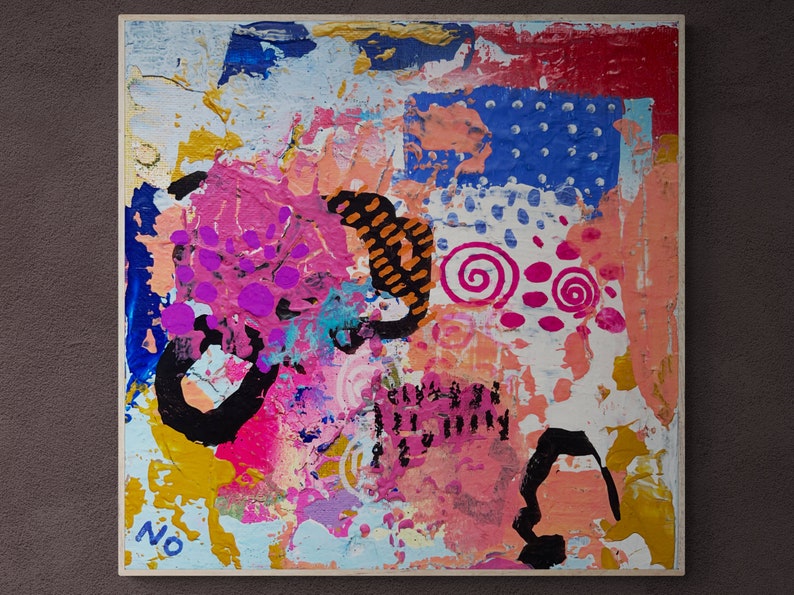 Op de afbeelding: Abstract schilderij op canvas met roze, blauwe, gele, oranje en zwarte verf. Het schilderij heeft een textuur en bevat swirls, stippen en lijnen.