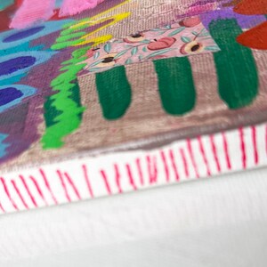 May include: A colorful abstract painting on canvas with a variety of shapes and patterns, including circles, lines, and floral designs. The painting is framed with a white border and has a red stripe along the bottom edge.