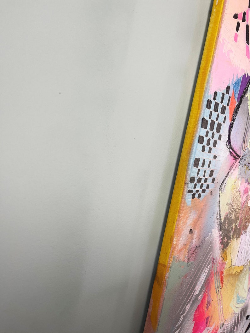 May include: A colorful abstract painting with a yellow frame. The painting features a variety of shapes and colors, including pink, blue, green, and black. The painting is textured and has a layered look.