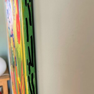 May include: A colorful abstract painting with a green background and black lines along the edge. The painting has a variety of colors, including yellow, orange, red, and blue.
