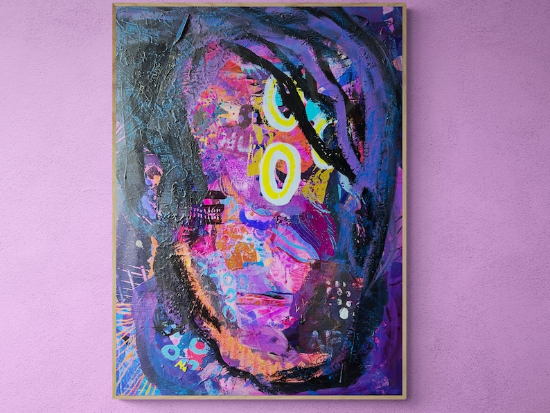 May include: Abstract painting of a person's face with purple, pink, blue, yellow, and black paint. The painting is framed in a wooden frame.