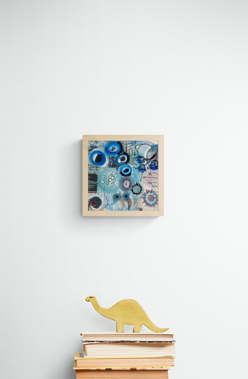 May include: A framed abstract painting in a blue, white and black colour scheme. The painting features a variety of shapes and patterns, including circles, swirls and lines. The frame is made of wood and has a natural finish.