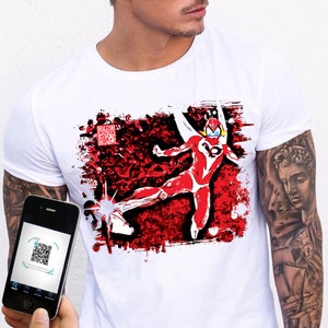 Può includere: Una t-shirt bianca a maniche corte con una stampa grafica di un supereroe rosso e bianco in una posa dinamica di calcio contro uno sfondo rosso e nero testurizzato, con un piccolo codice QR nell'angolo in alto a sinistra del disegno.