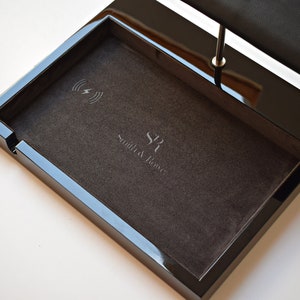May include: Black valet tray with a wireless charging pad and a watch stand. The tray has a black velvet lining and the text "Smith & Ross" is embossed on the bottom.
