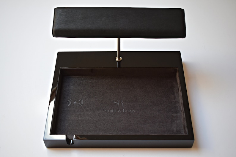 May include: Black valet tray with a wireless charging pad and a leather watch stand. The tray has a gray felt lining and the text "Smith & Jones" is embossed on the felt.