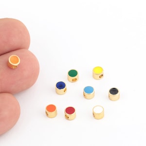 Puede incluir: Surtido de diez pequeñas cuentas redondas de color dorado con centros de esmalte de diferentes colores. Los colores incluyen rojo, naranja, amarillo, verde, azul, negro y blanco.