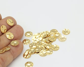 May include: A pile of gold-colored metal round discs with a hammered texture and a hole in the center.