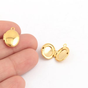 Peut inclure: Deux pendentifs médaillons ovales dorés avec une ouverture à charnière. Le médaillon de gauche est fermé, tandis que celui de droite est ouvert, révélant l'intérieur vide.