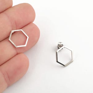 May include: A pair of silver hexagon stud earrings. The earrings are simple and modern, with a geometric design.