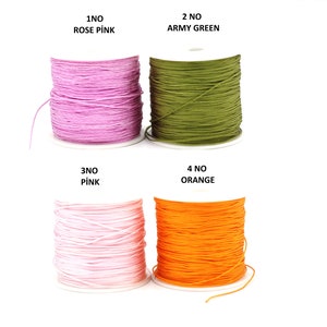 Könnte beinhalten: Vier Spulen elastischer Kordel in verschiedenen Farben: Rosarot, Armeegrün, Rosa und Orange. Die Spulen sind mit den Nummern 1 bis 4 und den Farbnamen beschriftet.