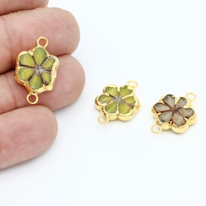 以下が含まれることがあります： 緑と茶色の樹脂製のインレイが付いた、ゴールドトーンの花の形をしたコネクターチャーム3個。各チャームには、ジュエリーに取り付けるためのジャンプリングが2つ付いています。