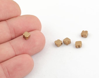 May include: Five gold-colored metal beads in the shape of a spade, a common playing card symbol. The beads are small and have a hole through the center for stringing.