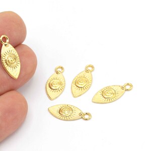 Puede incluir: Cinco abalorios de metal de color dorado en forma de ojo con un diseño en espiral. Los abalorios tienen un bucle en la parte superior para sujetarlos a joyas u otras manualidades.