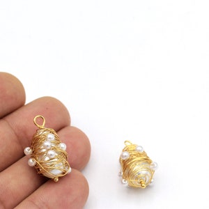 May include: Two gold wire wrapped pearl pendants with a white pearl in the center of each pendant. The pearls are surrounded by gold wire and small white pearls.