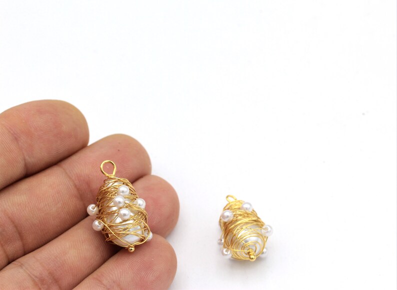 May include: Two gold wire wrapped pearl pendants with a white pearl in the center of each pendant. The pearls are surrounded by gold wire and small white pearls.