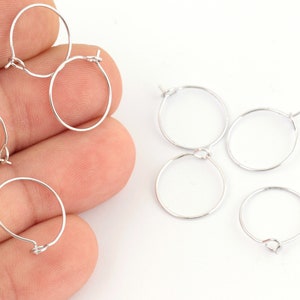 May include: A set of six silver hoop earrings with a hinged clasp. The earrings are arranged on a white surface.