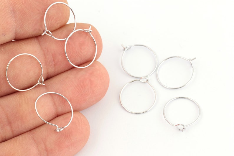May include: A set of six silver hoop earrings with a hinged clasp. The earrings are arranged on a white surface.