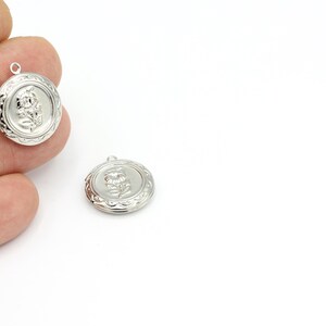 May include: Two silver-toned metal charms featuring a floral design. The charms have a loop at the top for attaching to a necklace or bracelet.