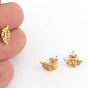 May include: A pair of gold-tone earrings with a leaf design and clear crystal accents.