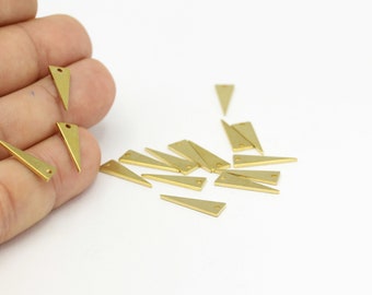 May include: A group of 15 gold-coloured triangle-shaped metal charms with a hole at the top. The charms are scattered on a white surface.