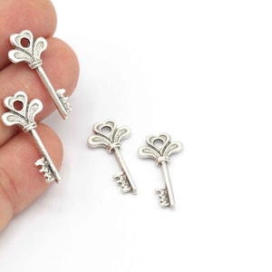 May include: Four silver-toned key charms with ornate designs. The keys have a decorative flourish at the top and a simple keyhole design at the bottom.