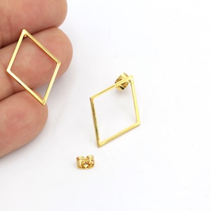 May include: A pair of gold-toned geometric diamond-shaped earrings. The earrings are made of a thin metal wire and have a simple, modern design.