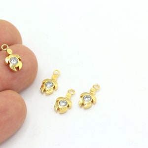 May include: Four gold-tone turtle charms with clear crystal accents. Each charm has a loop for attaching to a necklace or bracelet.