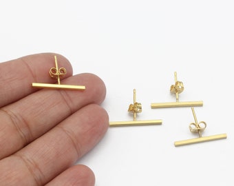 Può includere: Quattro orecchini a barra d'oro con un design semplice. Gli orecchini sono realizzati con una sottile barra di metallo dorato con un piccolo perno e un retro.