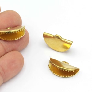 May include: Three gold-colored metal clasps for jewelry making. Each clasp is a half-circle shape with a small loop at the top for attaching a cord or chain.