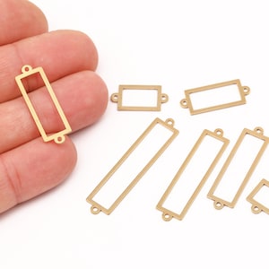 Op de afbeelding: Goudkleurige rechthoekige metalen bedels met open centra en kleine lussen aan elk uiteinde. Verschillende maten worden getoond. Deze bedels zijn geschikt voor het maken van sieraden en knutselen.