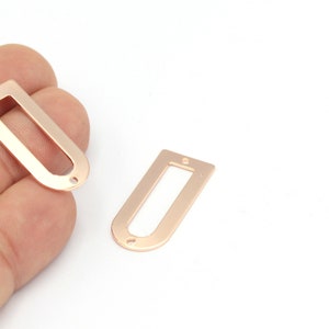 May include: Two rose gold metal rectangular frames with rounded corners and two holes on each side.