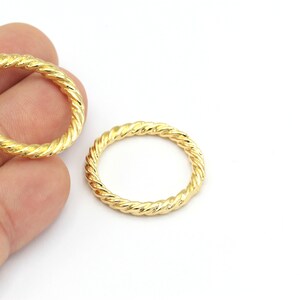 Puede incluir: Dos anillos de metal de color dorado con un diseño de cuerda trenzada.