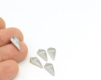 May include: Five silver heart-shaped charms with a floral design. The charms have a hole at the top for attaching to a necklace or bracelet.