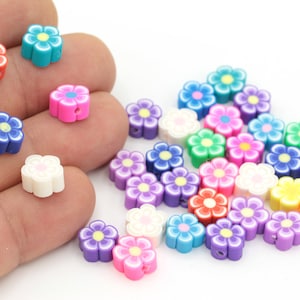 Puede incluir: Surtido de cuentas de arcilla polimérica con forma de flor de varios colores. Las cuentas son de varios colores, incluyendo rosa, morado, azul, verde, amarillo y blanco. Las cuentas tienen un agujero en el centro para enhebrarlas.