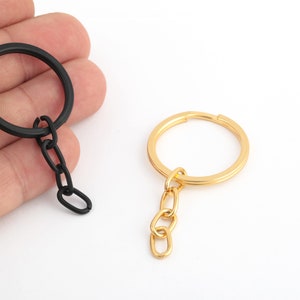 May include: Two keychains with metal rings and chains. One keychain is black and the other is gold.