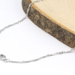 May include: A silver chain necklace with a lobster clasp closure. The chain is made of a twisted design.