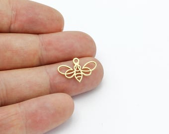 May include: Gold-colored metal bee charm with an outline design. The bee has wings and a body with stripes.