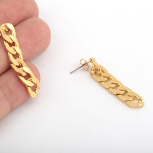 May include: A pair of gold chain link earrings. The earrings are long and dangle. The chain links are thick and chunky.