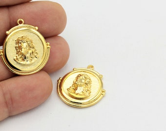 May include: Two gold-tone metal pendants featuring a raised image of Jesus Christ. Each pendant is round with a raised rim and a loop at the top for attaching to a chain.