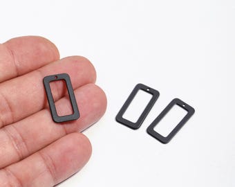 May include: Three small, matte black rectangular charms with a hole at the top for jewellery making. One charm is held in a hand, while two others are on a white surface. These charms are ideal for earrings or pendants.