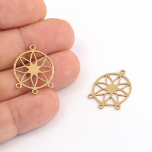 May include: Two circular brass charms featuring an intricate openwork star pattern. Each charm has a central eight-pointed star design enclosed within a ring, with three small loops extending from the bottom edge and one loop at the top.