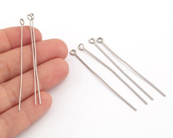 May include: Silver head pins with a loop at one end. The pins are about 2 inches long and are arranged in two groups on a white surface.