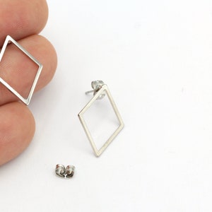 May include: A pair of silver diamond-shaped earrings with a simple, minimalist design.