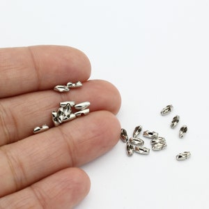 May include: A close-up of a pile of silver-toned metal chain links. The links are small and oval-shaped, with a slightly textured surface.