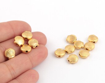 May include: A group of gold-colored metal seashell beads. The beads are about 1 cm in diameter and have a hole in the center for stringing.